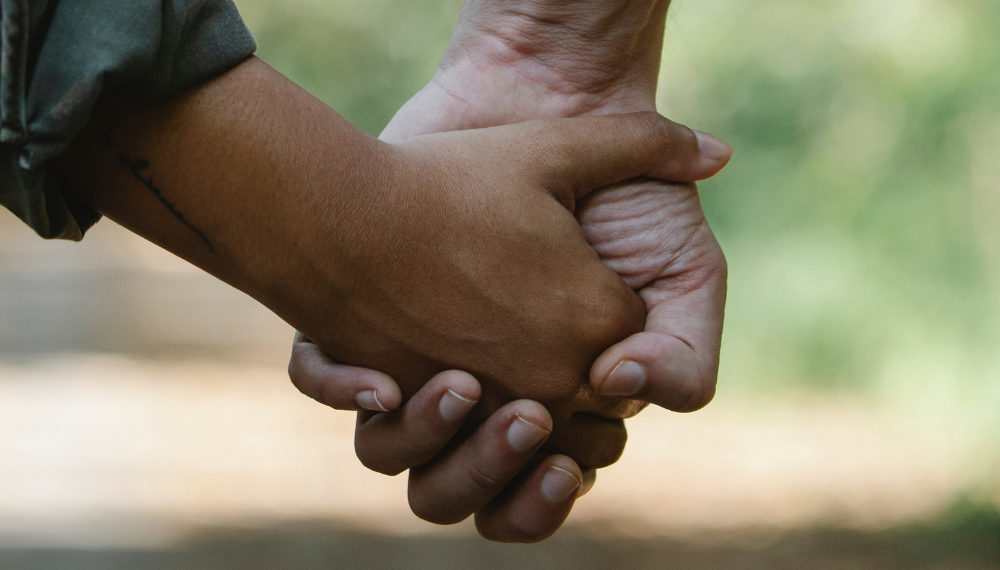 Close up image of two people holding hands.